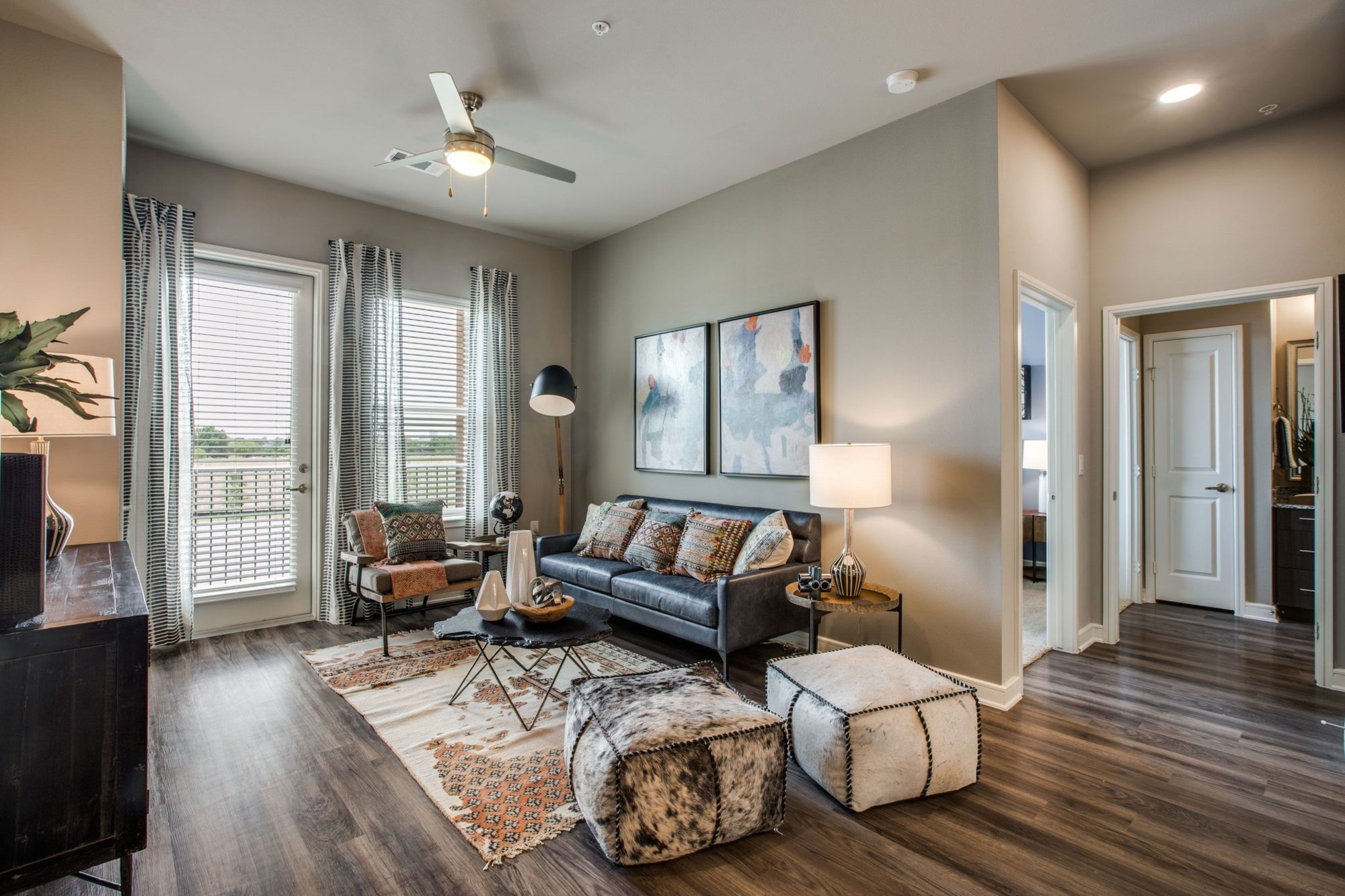 living area with dual windows, patio access, ceiling fan, wood flooring, and decor